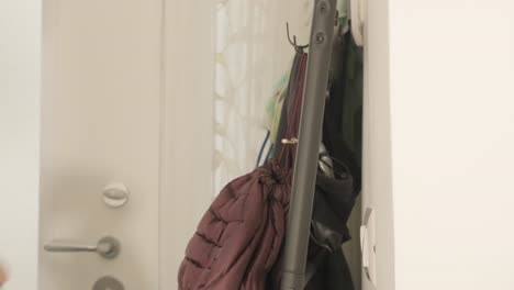 a man coming back home, removing his stylish leather jacket and hat, putting them on a rack