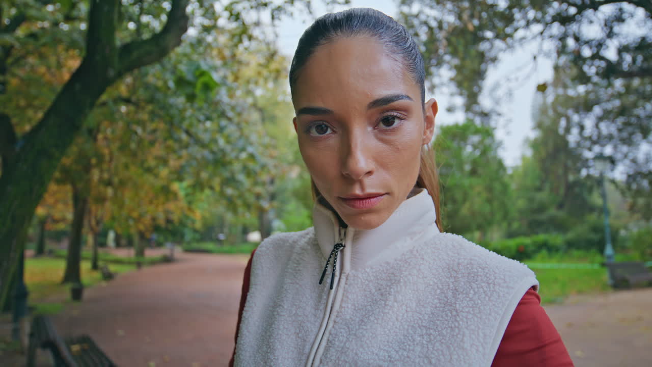 Bella atleta che si rilassa nel parco, in piedi su un sentiero dopo la corsa, primo piano.