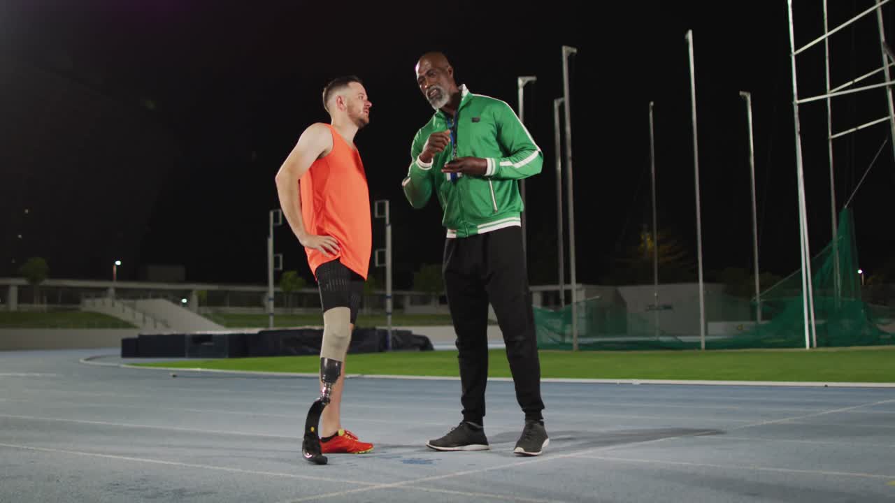 Diverse male coach and disabled male athlete with running blade standing and talking