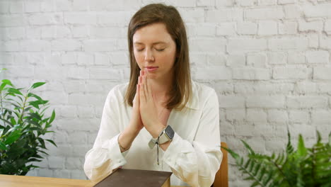 A-young-woman-praying-with-a-bible-and-hands-flat-together-in-prayer