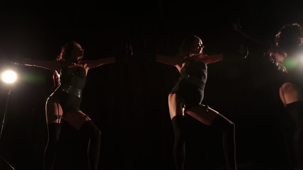 Dancing girls in stockings on black background
