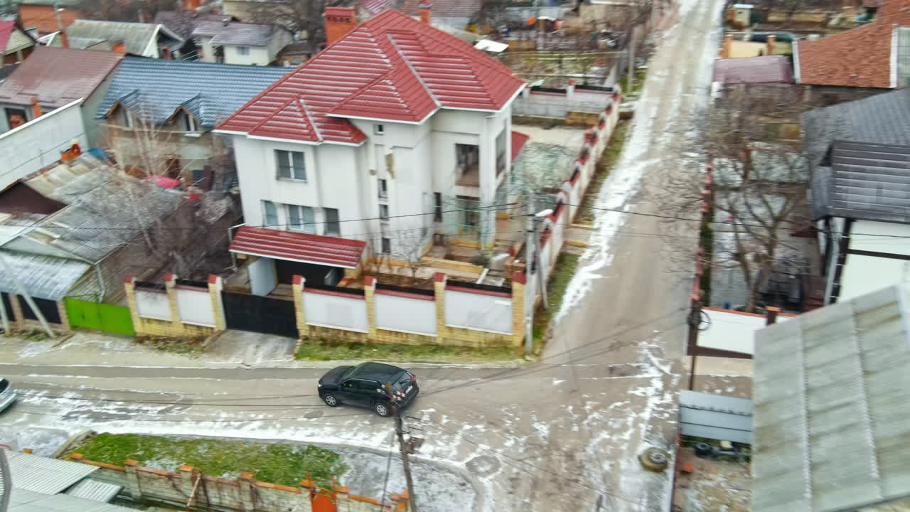 Aerial drone view of a residential distict in Chisinau, Moldova. Multiple buildings, road, moving car, Cloudy weather, bare trees, winter