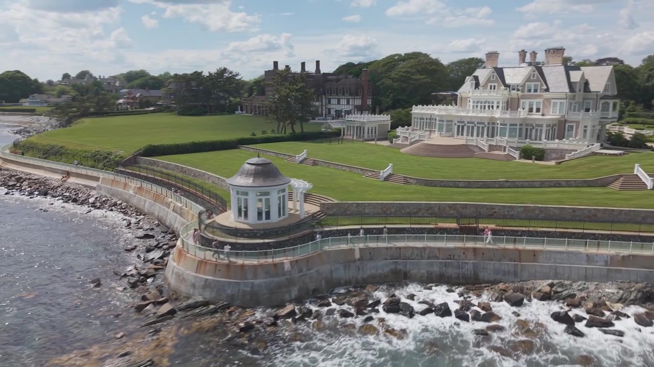 Newport Rhode Island Cliff Walk promenade, storslået Tudor-palæ, velplejet græsplæne, klippefyldt kystlinje, havbølger, kyststi, historisk ejendom, New Englands kystlinje. Luftfoto fra drone
