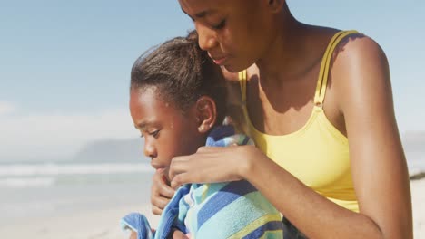 Afroamerikanische-Mutter-Trocknet-Ihre-Tochter-Mit-Einem-Handtuch-Am-Strand