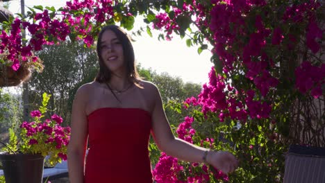 a young caucasian female model poses in front of a colorful flower terrace