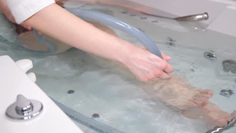 a young woman lies on her back in a bathtub during a hydromassage. professional water procedures. peeling procedure for weight loss and rejuvenation. vertical video