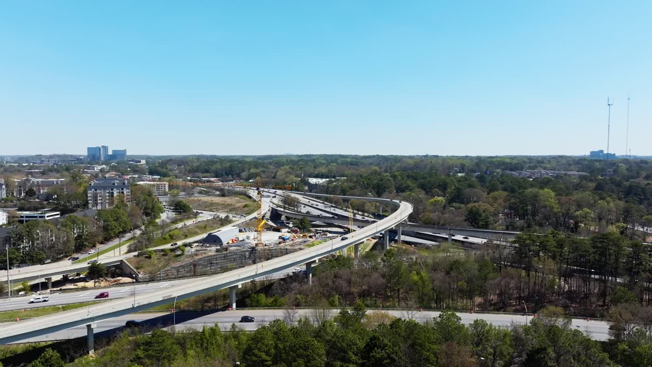 Aerial wide shot of elevated highways in Atlanta City at sunny day with blue sky. Cars on highway in america during sunny day. Construction site with crane.