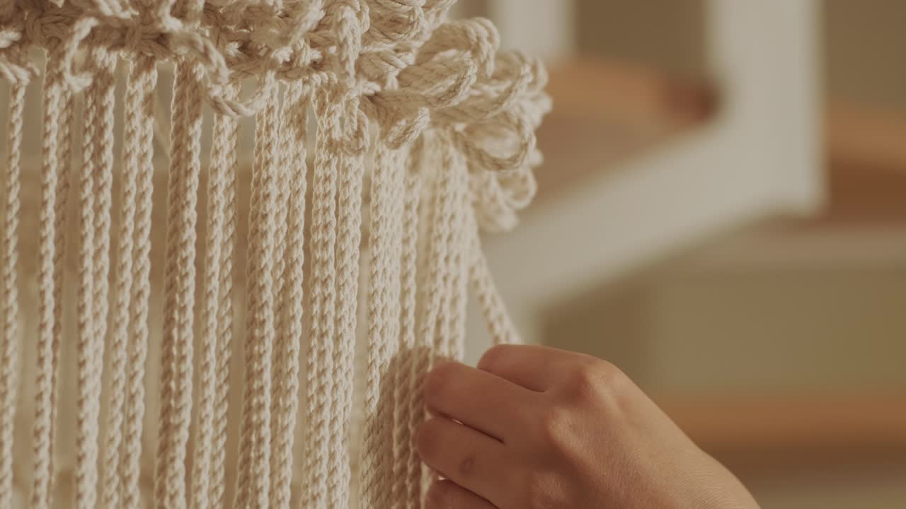 집에서 마크라메를 뜨개질하는 취미. 여성의 손은 두꺼운 가닥으로 장식을 뜨개진다.