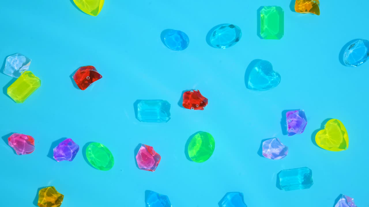 많은 다채로운 보석들이 파란 물로 바다 바닥에 놓여 있습니다.