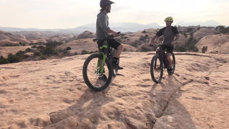 two athletic male mountain bikers reaching the top