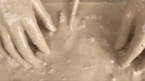 Close-Up-of-a-boy-with-wet-muddy-hands,-playing-with-wet-clay