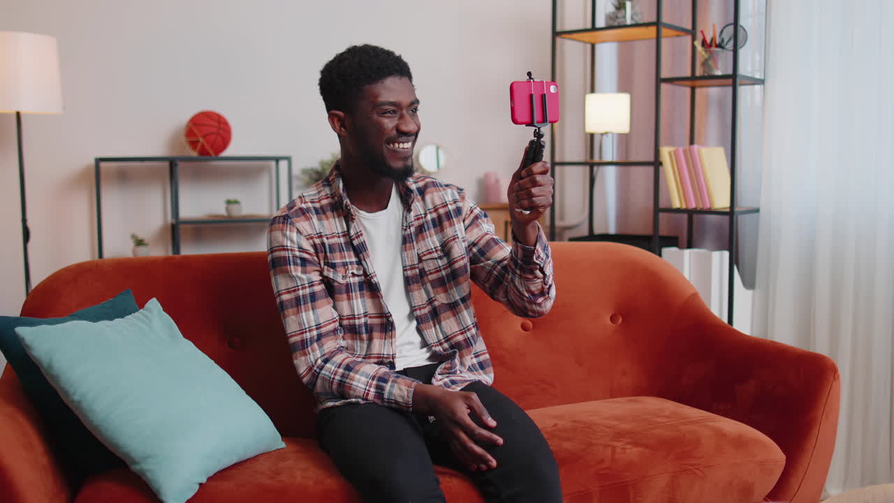 Uomo blogger e influencer che si scatta un selfie con lo smartphone, realizzando un video per i social media da casa.