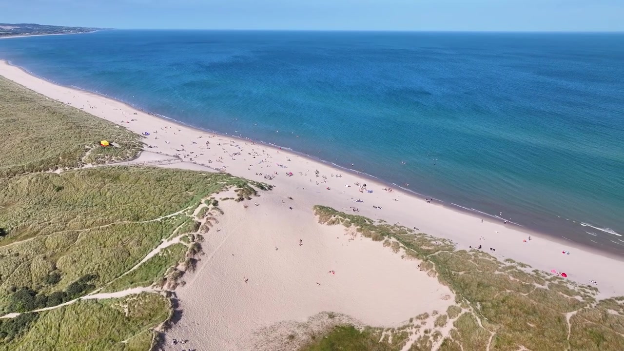 Folk slapper af på Curracloe Strand en solrig sommer eftermiddag i Wexford, Irland