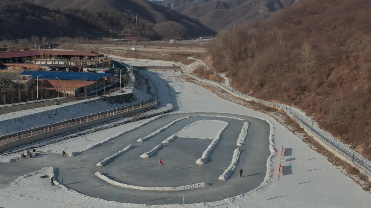 Descending shot of skater on ice rink in the middle of a frozen river. 4K