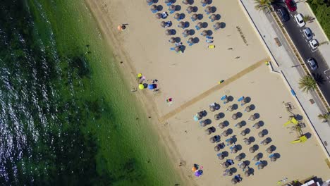 Orbiting-drone-shot-slowly-descending-down-the-beachfront-of-Playa-del-Port-de-Pollen,-located-in-the-island-of-Mallorca,-Spain