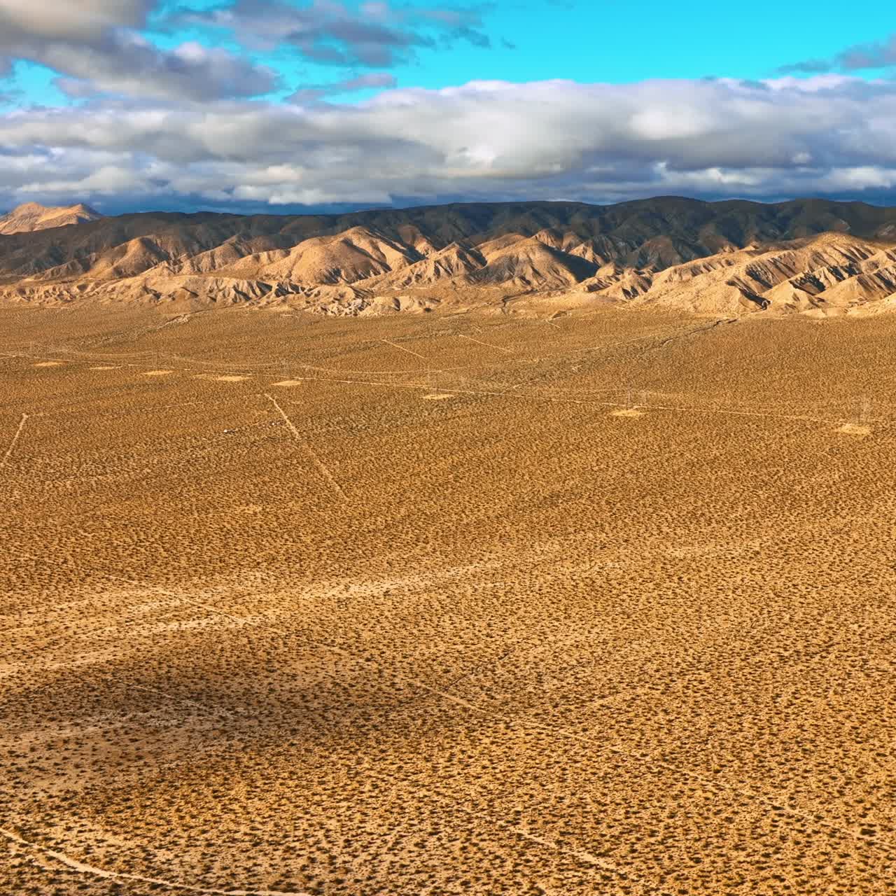 Beautiful scenery of Nevada desert on daytime. Drone footage approaching stunning mountains topped with clouds