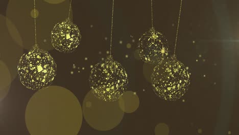 animation of gold christmas baubles swinging over stars and light spots on brown background