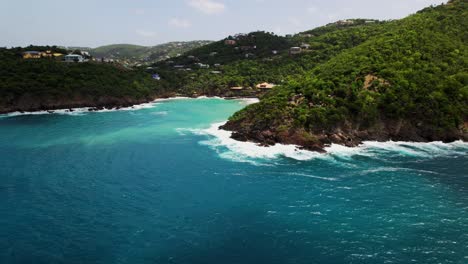 gorgeous aerial view circling bluff water crashing on rocks homes in background blue sky turquoise water hills cliff