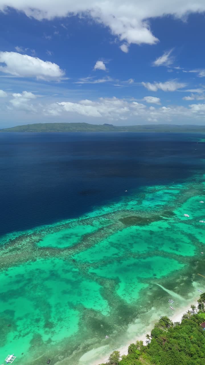 Drone che scende in verticale ed effettua una panoramica a sinistra sulle piattaforme coralline di Panglao Beach a Panglao, Bohol.