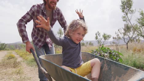 happy caucasian father and son pushing wheelbarrow