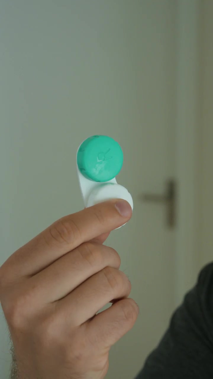 Close-up of a hand holding a contact lens case, showing eye care, hygiene, vision correction, and daily personal routine.