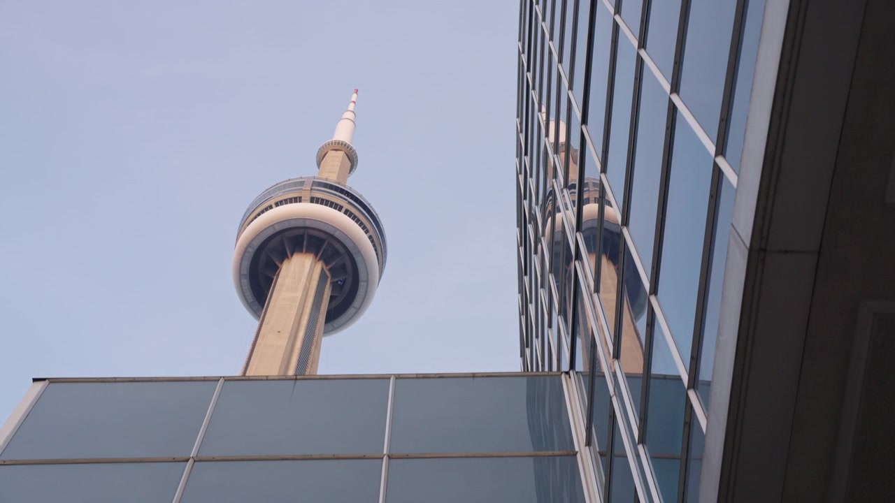 Riflesso della CN Tower nella facciata di un grattacielo di vetro nel centro di Toronto. Movimento lento.