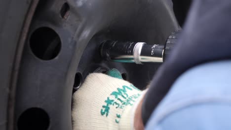 extreme close up, mechanic unscrews a winter tire with an electric impact wrench