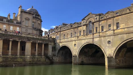 View-Of-Victoria-Art-Gallery-With-Dome-Roof-At-The-End-Of-Pulteney-Bridge-Spanning-Across-River-Avon-In-Bath,-Somerset,-England---low-angle-shot