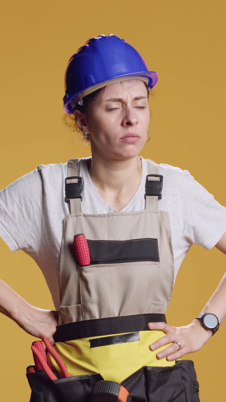 Vertical video: Portrait of sleepy tired handywoman working on construction