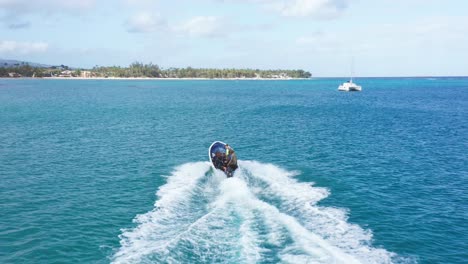 toma aérea de una lancha rápida que cruza el mar caribe de color azul durante la luz del sol