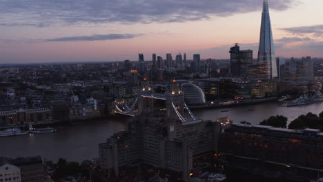 Slide-and-pan-shot-of-evening-cityscape.-Illuminated-Tower-Bridge-and-Shard-skyscraper-on-south-bank-of-River-Thames.-London,-UK