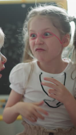 couple of cheerful children has fun together slow motion. boy and girl hold hands laughing and make funny faces. children make noise resting at home closeup