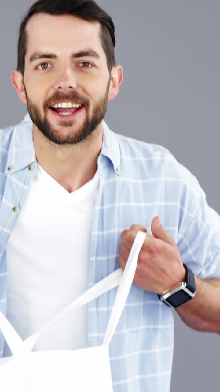 hombre sosteniendo una bolsa de mano sobre fondo gris