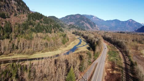 Cinematic-Scene-of-the-Lougheed-Highway-7-in-the-Fraser-Valley-in-the-Lower-Mainland-in-British-Columbia-Canada,-bright-scene-on-a-sunny-day-in-fall-with-cars-driving-the-road-with-majestic-mountains