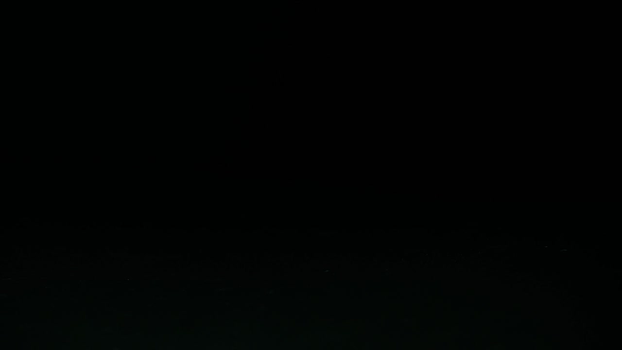 green yellow pear falls clumsily in front of black background on dark background and remains standing slow motion