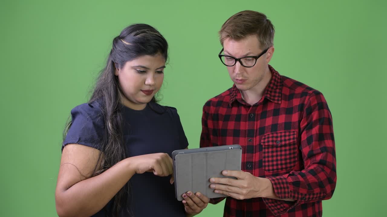 joven pareja de negocios multiétnica juntos contra un fondo verde