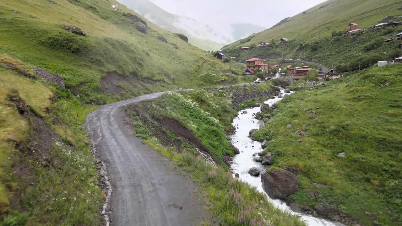 drone scatto di un'auto che guida di strade villaggi fiume montagne caucasiche