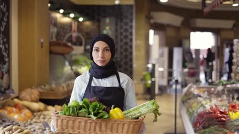 muslim woman in hijab walks with basket of fresh vegetables in the supermarket