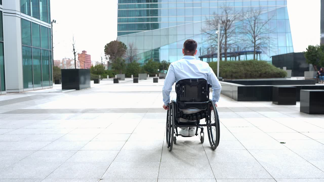 Rear View of Man in Wheelchair Moving in Modern City