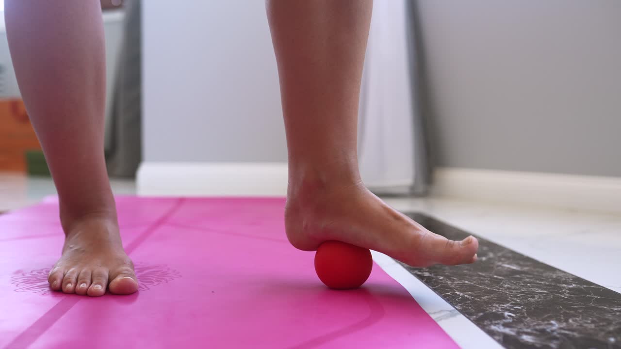 masaje de pies con una pelota en la alfombra de yoga