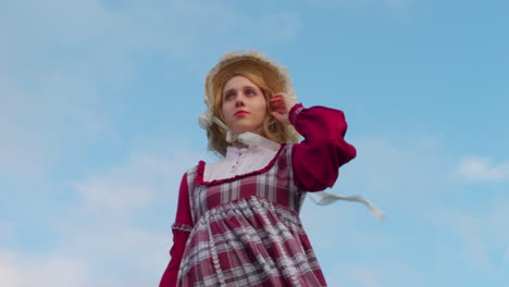 attractive-sexy-blonde-caucasian-female-model-in-traditional-old-style-fashioned-clothing-dress-in-windy-countryside-low-angle-view