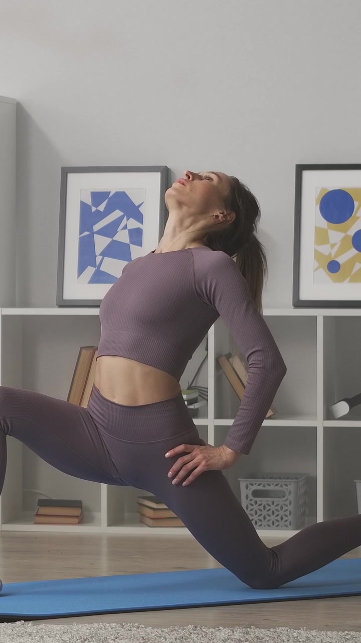 Mulher de roupa esportiva alongando-se em um tapete de yoga em casa.