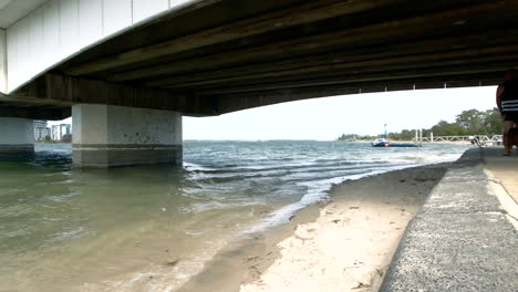 paradise point beach waves washing a shore under bridge