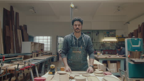 young carpenter posing at workplace in woodshop