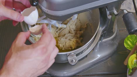 cracking and adding the second egg to a cookie dough mixture