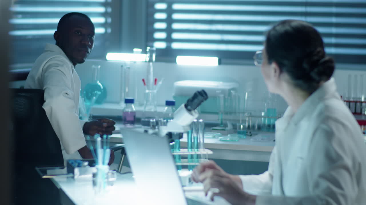 Female Chemist Using Laptop and Talking with Colleague