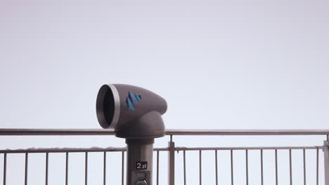 Snowy-mountain-ski-resort-observation-telescope-spinning-on-pedestal-surrounded-by-winter-landscape