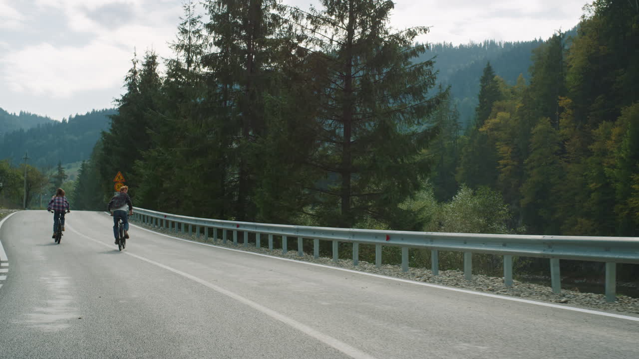 라이더 들 은 여름 숲 에 있는 산 풍경 을 자전거 로 타고 있다. 친구 들 은 도로 에서 자전거 를 타고 있다