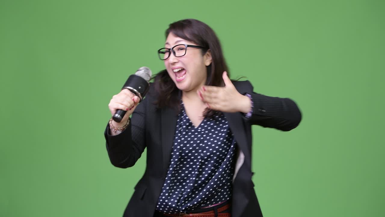 성숙하고 아름다운 아시아 사업가 여성이 마이크를 사용합니다.