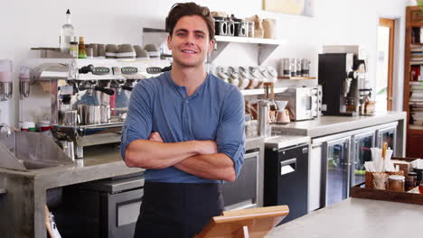 Macho-Joven-Propietario-De-Una-Cafetería-Cruzando-Los-Brazos-Detrás-Del-Mostrador